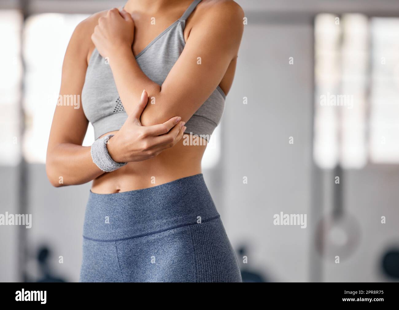 Nahaufnahme einer weißen Frau, die ihren schmerzenden Ellbogen während des Trainings in einem Fitnessstudio hielt. Sportlerin mit schmerzhafter Armverletzung durch Gelenkfraktur und Muskelentzündung während des Trainings. Schwierigkeiten mit steifen Krämpfen, die Unbehagen und Belastungen verursachen Stockfoto