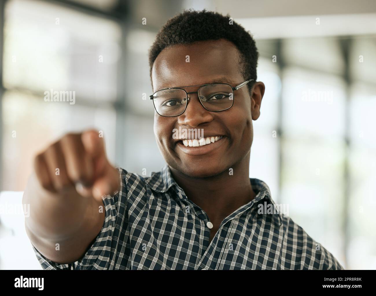 Porträt eines selbstbewussten jungen afroamerikanischen Geschäftsmanns mit Brille, die Zeigefinger auf die Kamera zeigt, während sie in einem Büro steht. HR-Manager wählt Sie Stockfoto