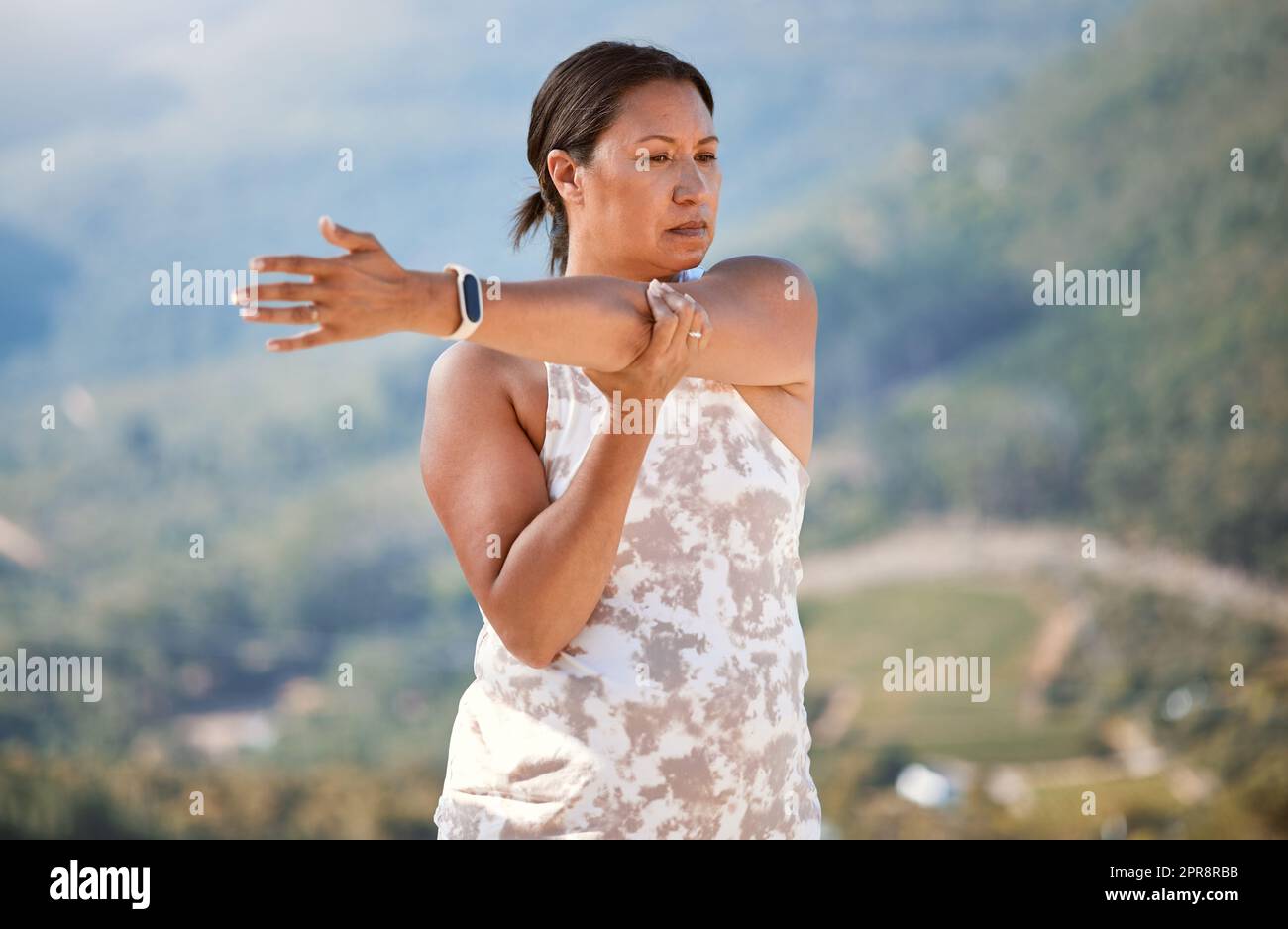 Reife Mischrasse Frau streckt ihre Arme während der Ausübung in der Natur. Frau, die im Freien Yoga macht und einen gesunden und aktiven Lebensstil lebt Stockfoto