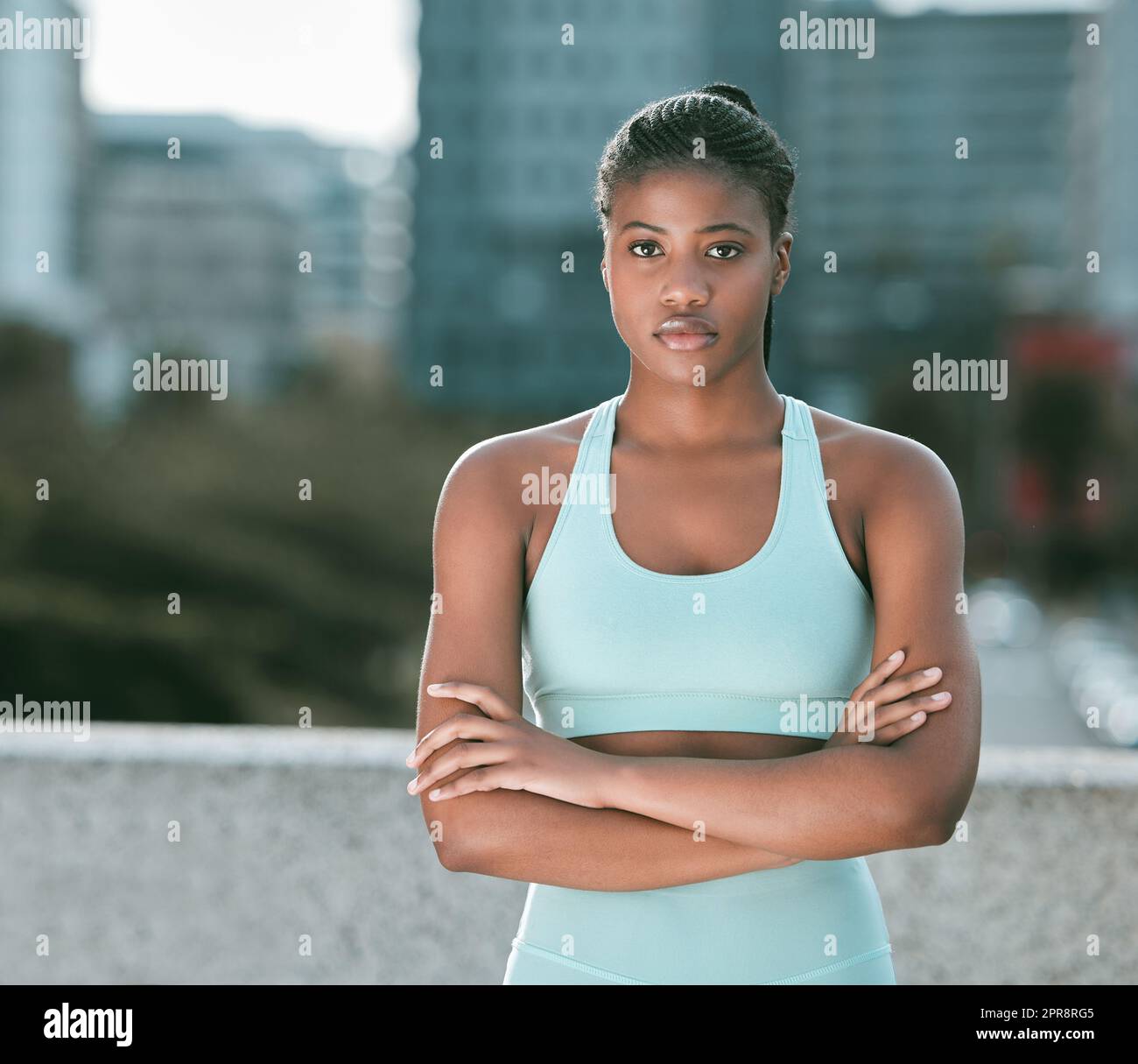 Porträt einer jungen afroamerikanischen Frau, die mit gekreuzten Armen steht, bereit für Sport im Freien. Entschlossene Sportlerin, die fokussiert und motiviert für das Training in der Stadt aussieht Stockfoto