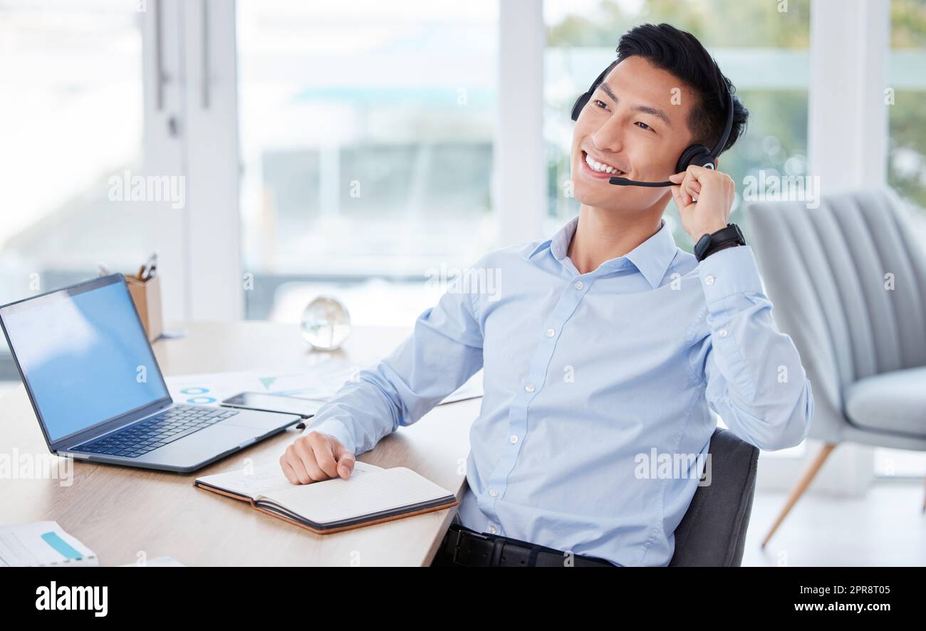 Denken Sie an die Zukunft: Ein junger männlicher Callcenter-Agent, der einen Laptop benutzt und bei der Arbeit in einem Notebook schreibt. Stockfoto