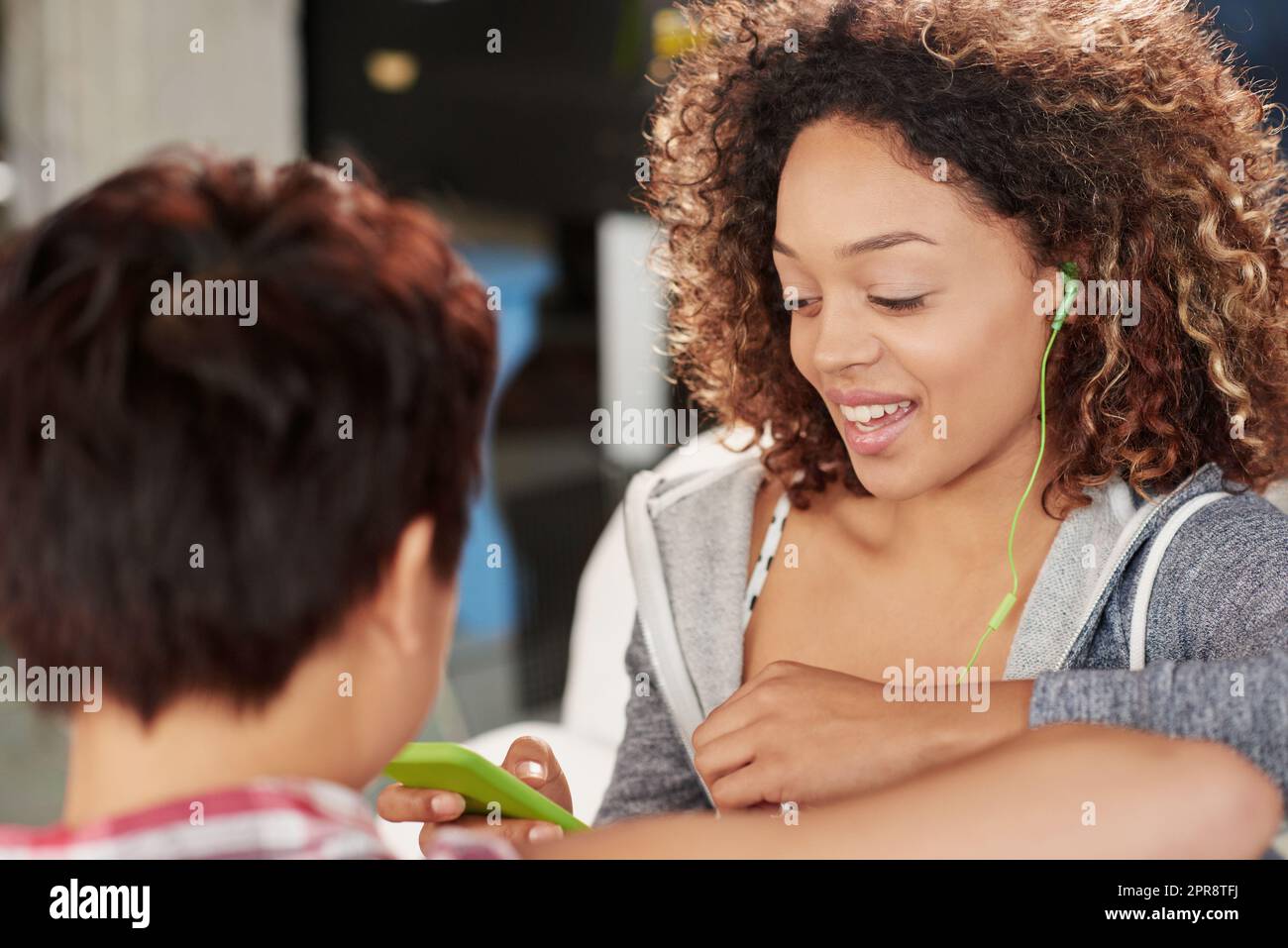 Jeder weiß, wie sehr ich meine Musik liebe. Zwei Freunde hören Musik auf einem Handy, während sie zu Hause auf der Couch sitzen. Stockfoto