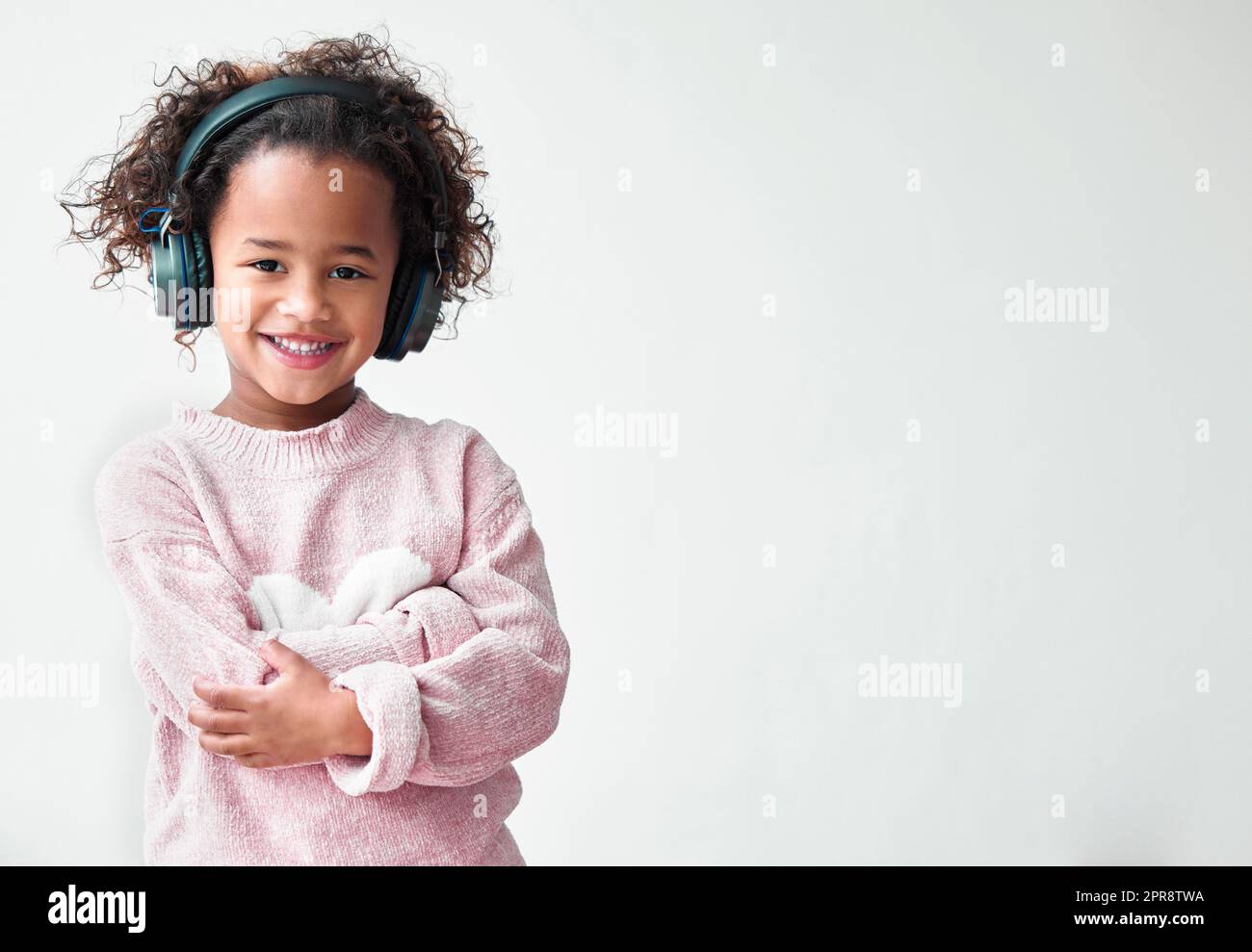 Eine Tochter ist ein Haufen von Aufsehern, die begeistern. Ein kleines Mädchen, das mit gekreuzten Armen vor einem grauen Hintergrund steht. Stockfoto