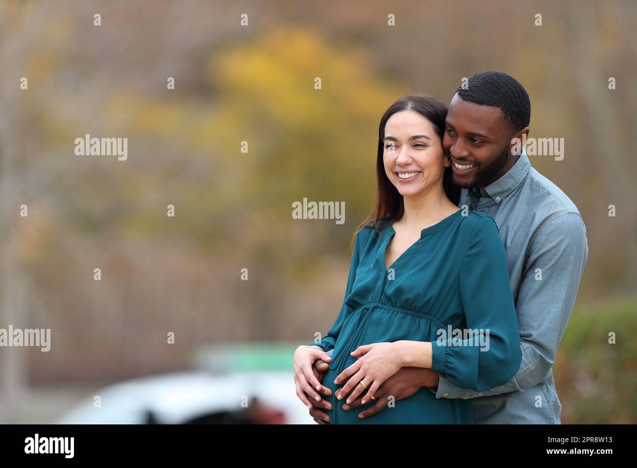 Gemischtrassiges Paar, das wegschaut und eine Schwangerschaft genießt Stockfoto