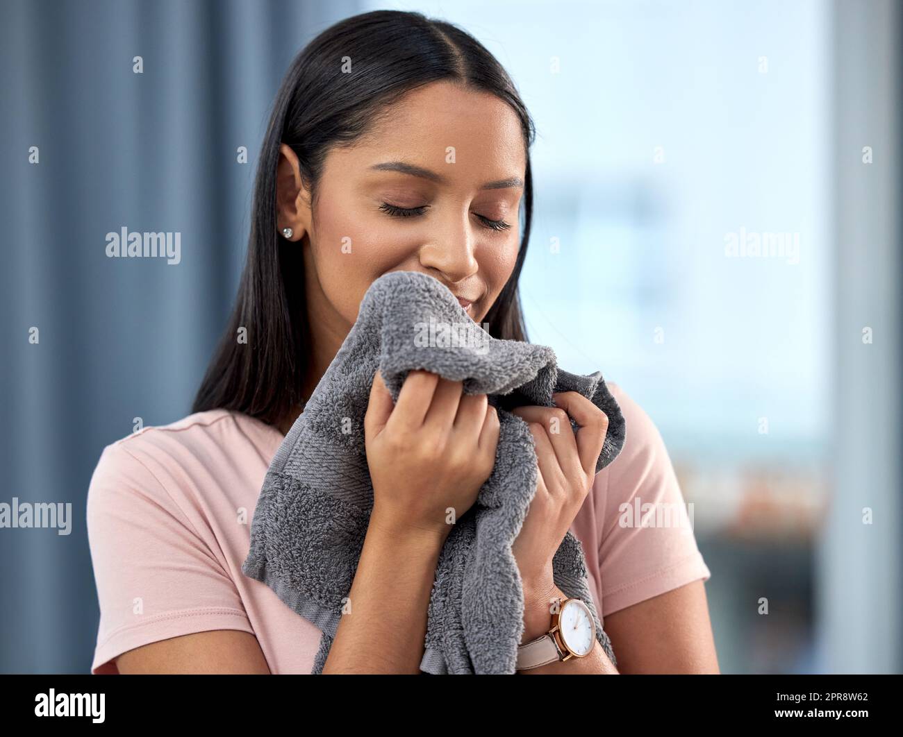Wenn Ihre Umwelt sauber ist, fühlen Sie sich glücklich motiviert und gesund. Eine junge Frau riecht zu Hause ein Handtuch. Stockfoto
