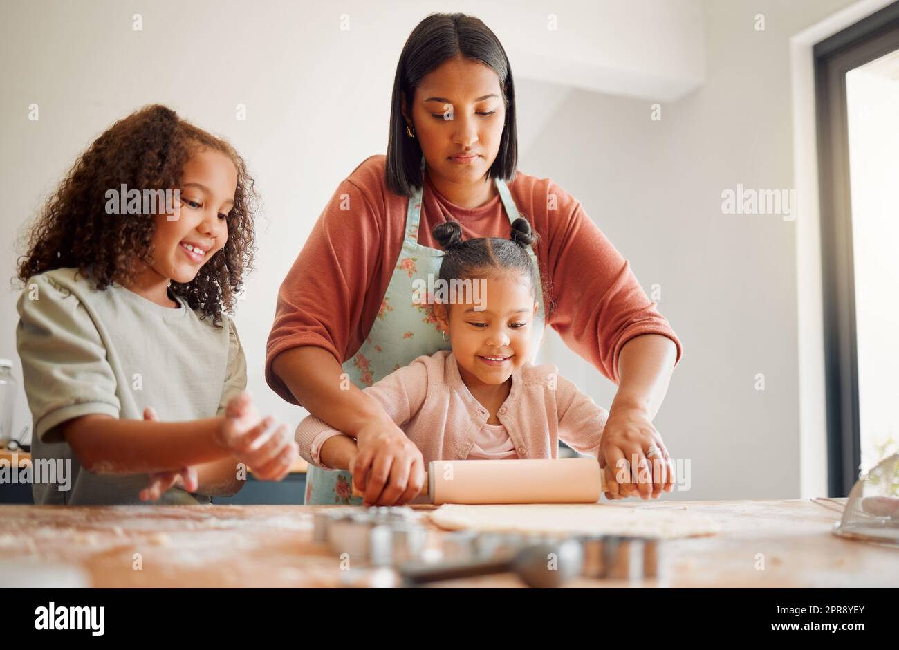 Nur Frauen, glückliche Mischrasse, dreiköpfige Familie, die in einer chaotischen Küche kocht. Liebe schwarze alleinerziehende Eltern, die sich mit ihren Töchtern verbinden und ihnen häusliche Fähigkeiten zu Hause beibringen Stockfoto