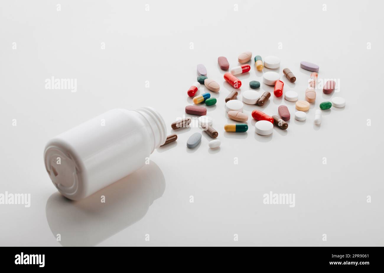 Eine Pille kann dein Leben verändern: Eine Pillenflasche liegt auf der Seite und in einem leeren Studio wird Medizin ausgegossen. Stockfoto