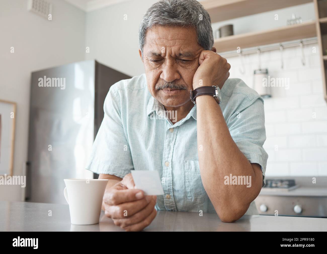 Es wird mit der Zeit besser. Ein älterer Mann, der unglücklich aussieht, während er zu Hause ein Foto ansieht. Stockfoto