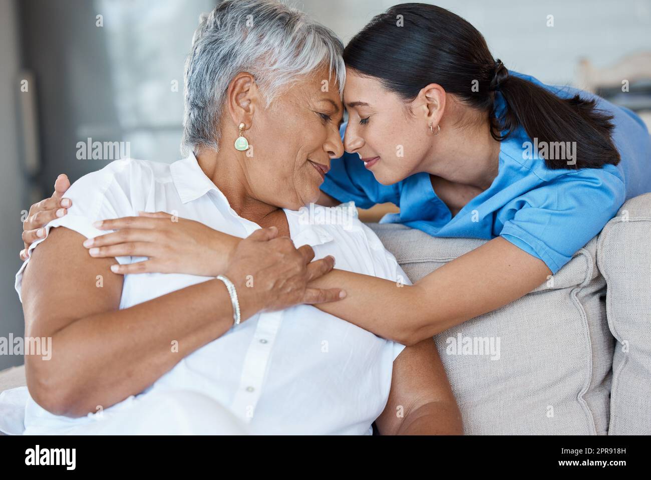 Alles, was Sie brauchen ... eine attraktive junge Krankenschwester, die einen intimen Moment mit ihrer älteren Patientin teilt. Stockfoto
