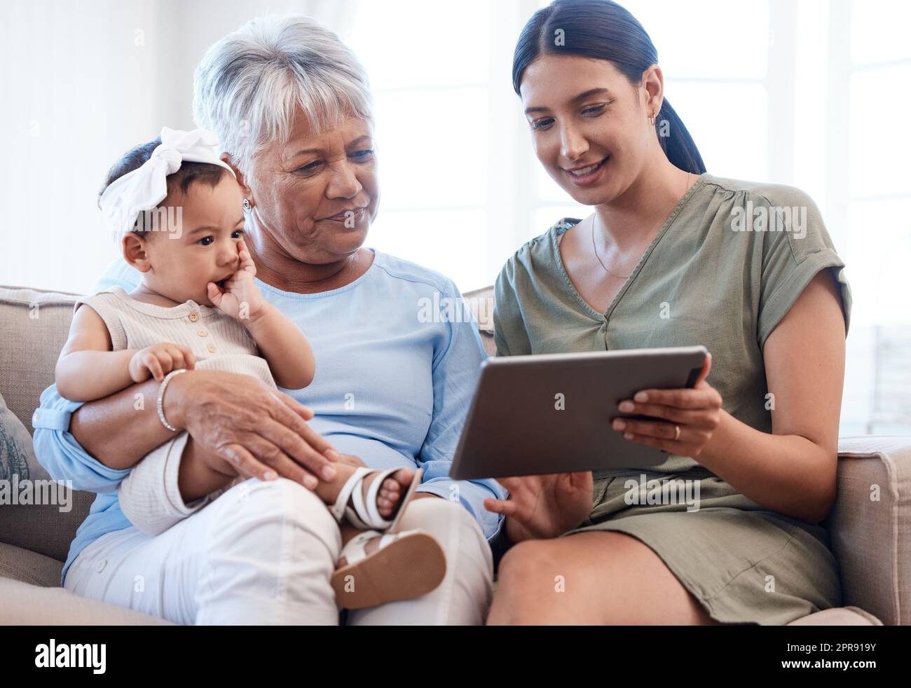 In den Armen von Nana. Eine reife Frau, die sich mit ihrer Tochter und Enkelin auf dem Sofa verklebt. Stockfoto