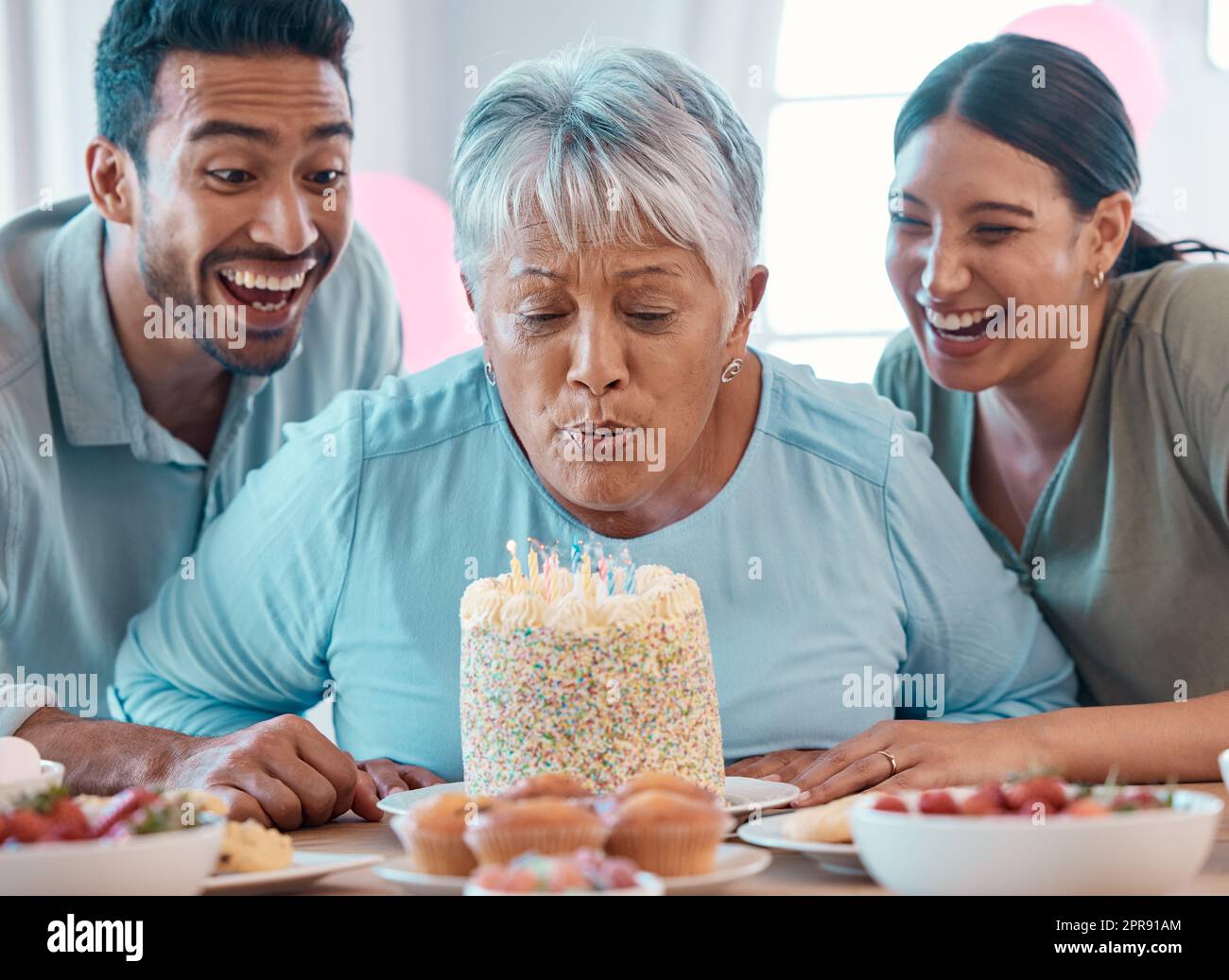 Zwei junge Erwachsene feiern einen Geburtstag mit einer reifen Frau zu Hause. Stockfoto