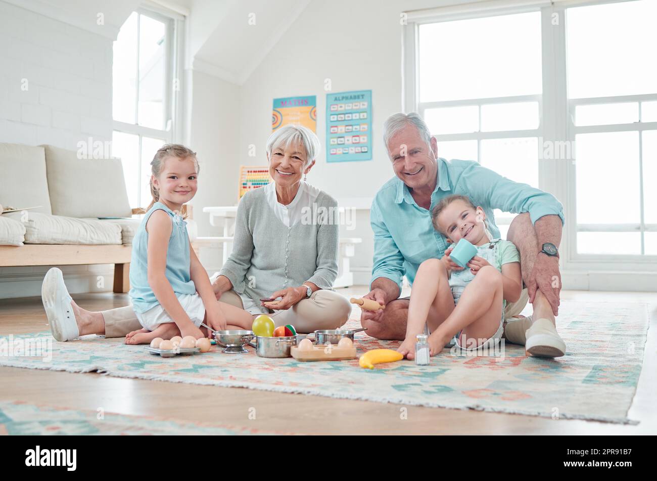 Unser Großeltern-Haus ist wie unser zweites Zuhause. Zwei kleine Mädchen spielen mit ihren Spielsachen, während sie zu Hause mit ihren Großeltern sitzen. Stockfoto