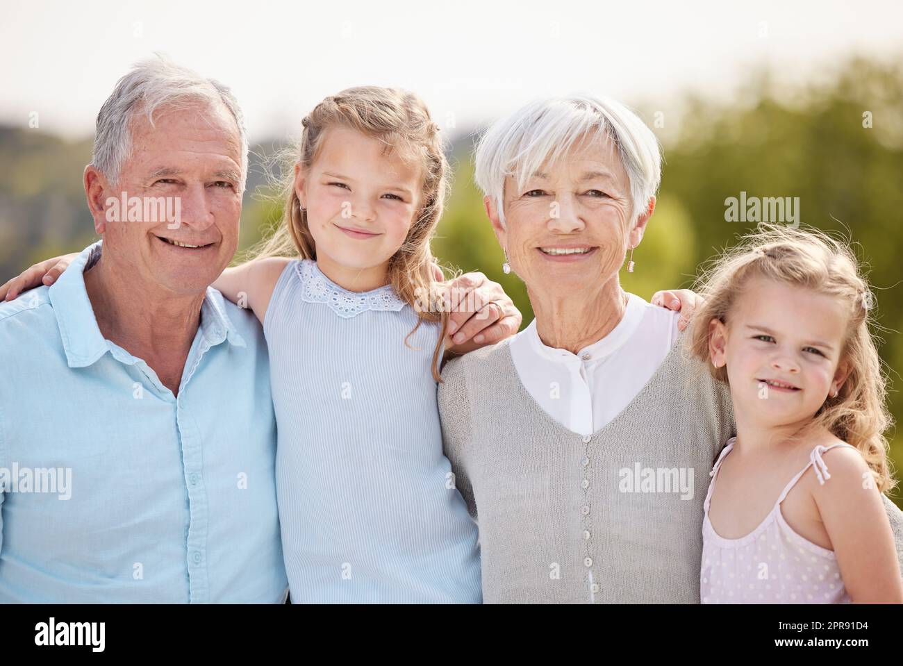 ... Ein liebevolles reifes Paar und ihre Enkelinnen in einem Park. Stockfoto