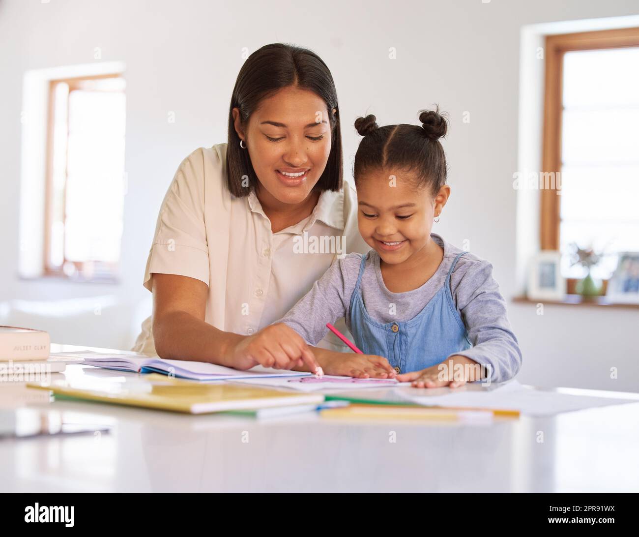 Gemischte Rassenmädchen lernen und lernen mit mom im Hausunterricht. Eine Frau, die ihrer Tochter bei Hausaufgaben und Aufgaben zu Hause hilft. Liebevolle Eltern bringen einem glücklichen Kind Farbe und Schreibkunst bei Stockfoto
