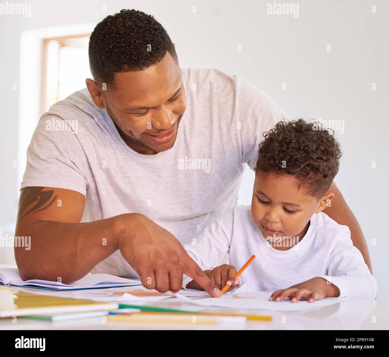 Gemischter Rassenjunge, der mit Dad im Hausunterricht lernt und lernt. Ein Mann, der seinem Sohn bei Hausaufgaben und Aufgaben zu Hause hilft. Eltern bringen dem Kind bei, zu Hause zu malen und zu schreiben, während es abgeriegelt ist Stockfoto