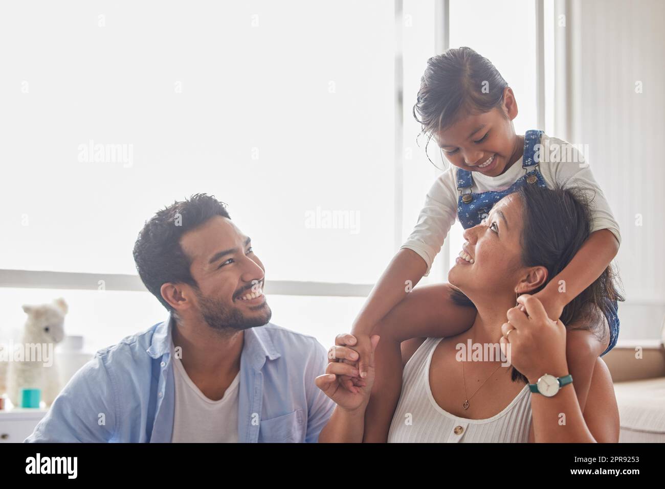 Junges glückliches Paar, das mit seinem kleinen Mädchen die Zeit der Familie genießt und zu Hause fröhlich aussieht Stockfoto