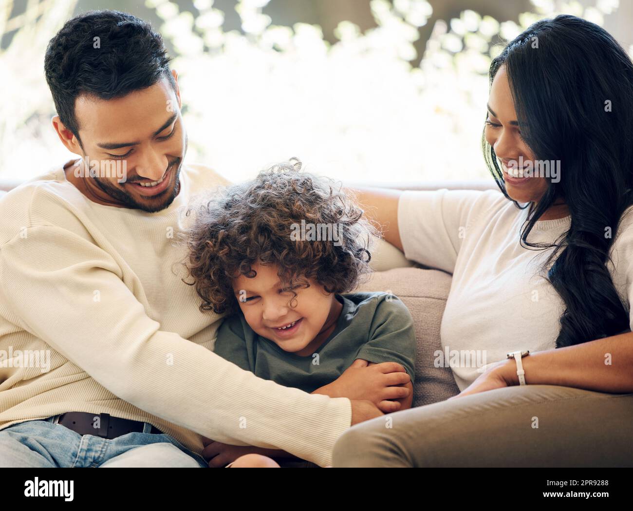 Kitzeln ist unsere Liebessprache. Ein Paar, das sich zu Hause mit ihrem Sohn verfreundet. Stockfoto