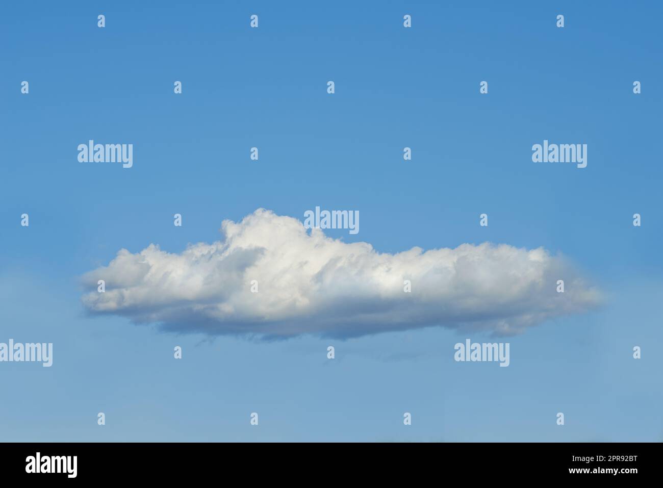 Kopieren Sie den Raum mit einer Wolke, isoliert vor einem klaren blauen Himmel an einem sonnigen Tag draußen. Eine einzige flauschige und weiße Wolke schwebt in einer friedlichen Tapete und ruhigen Szene für den Naturhintergrund Stockfoto