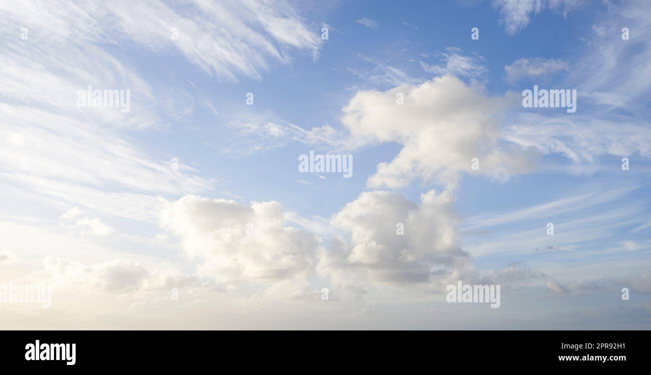 Wolkiger blauer Himmel mit flauschigen Wolken als natürlicher Hintergrund an einem Sommertag. Querformatansicht der Kumulusbildung mit Kopierbereich. Schöne Aussicht auf die Atmosphäre und das Klima Stockfoto