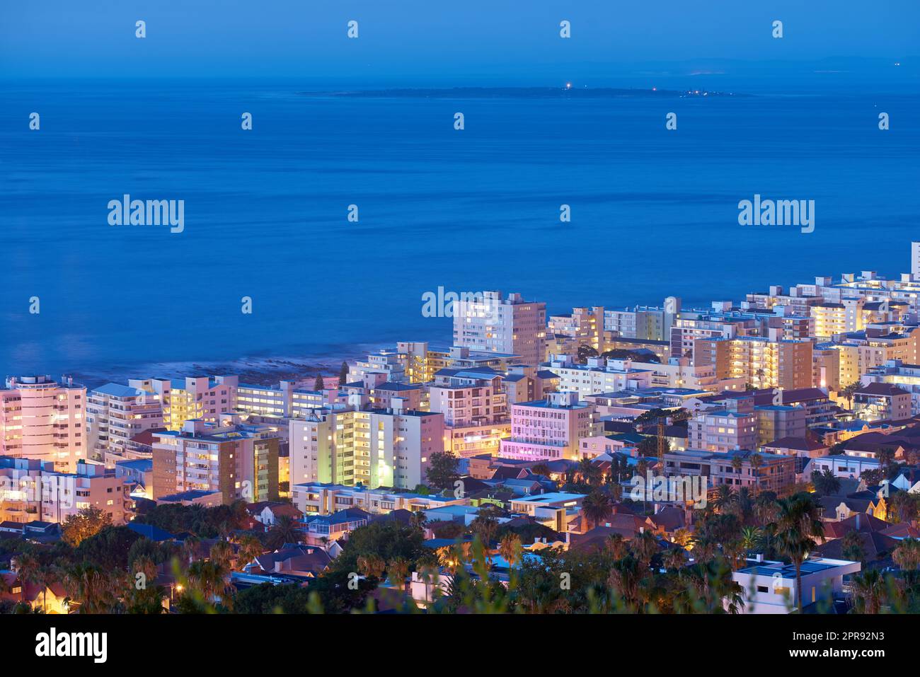 Wunderschöner Sonnenuntergang über einem Stadtbild, wie er vom Signal Hill in Kapstadt, Südafrika, aus zu sehen ist. Malerische Panoramalandschaft aus Lichtern, die eine städtische Skyline am Meer erleuchten Stockfoto