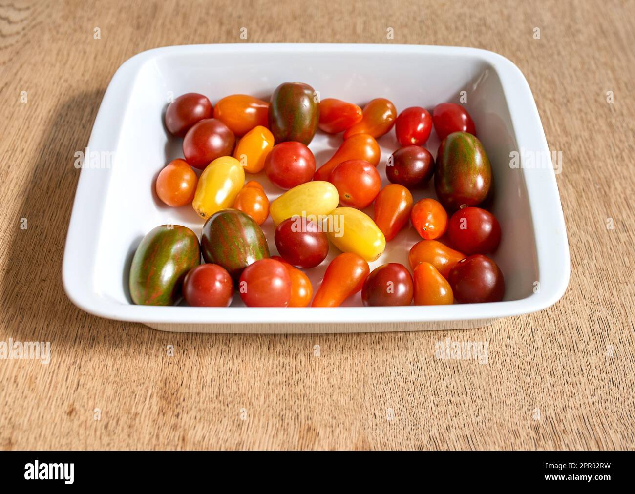 Viele Kirschtomaten in einer Schüssel. Viel buntes Bio-Tomatengemüse für eine gesunde vegetarische Platte. Buntes kleines köstliches Obst, perfekt für vegane vegetarische Speisen, Vorspeisen oder Snacks Stockfoto