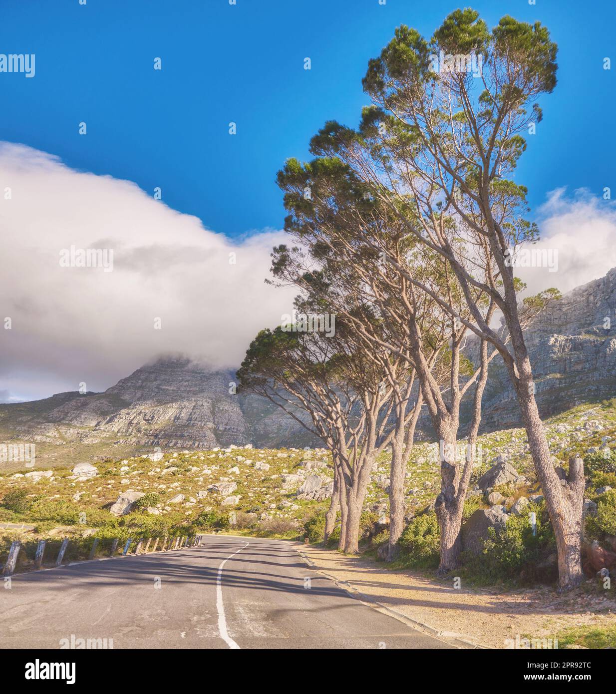 Roadtrip durch die Berglandschaft auf der Teerstraße oder der Straße mit blauem Himmel im Sommer an einem beliebten Reiseziel. Fahren Sie auf dem Pfad zu malerischen grünen Hügeln für Wochenendausflüge oder Fahrten Stockfoto