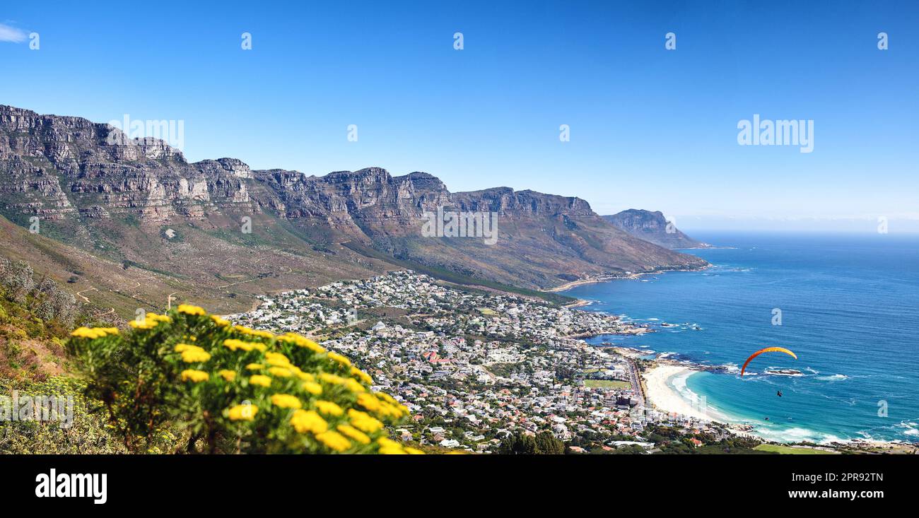 Landschaft einer Gebirgskette in der Nähe einer Küstenstadt vor einem blauen Horizont im Sommer, südafrikanisch. Weitwinkeltapete der zwölf Apostel in der Nähe des ruhigen Meeres und beliebter Reiseort für Werbetexte Stockfoto