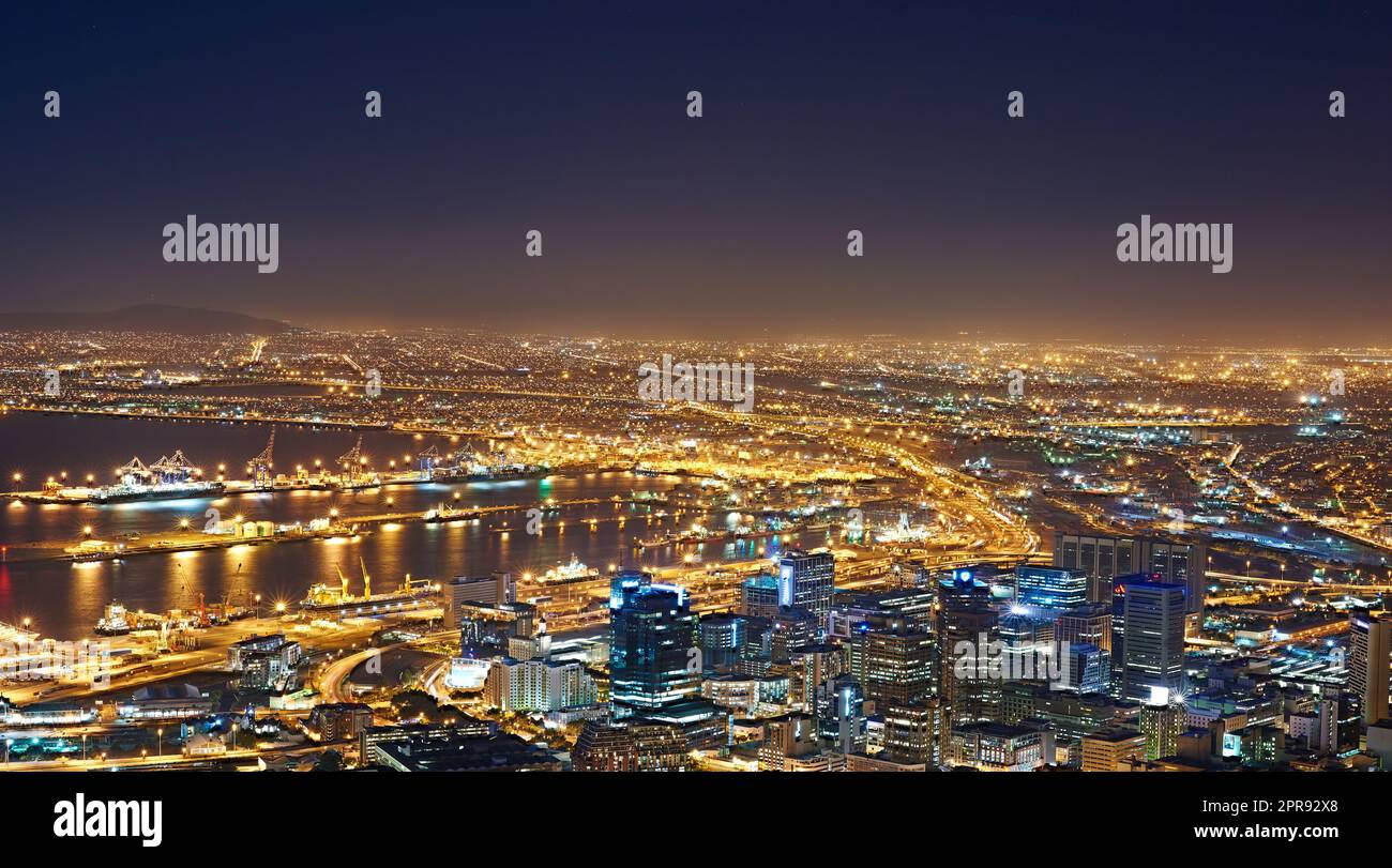 Landschaft mit Nachtlichtern in Kapstadt, Südafrika, mit Kopierbereich. Nächtliche Stadtlandschaft eines modernen Urlaubs- oder Urlaubsziels. Eine helle und lebendige Skyline bei Sonnenuntergang Stockfoto