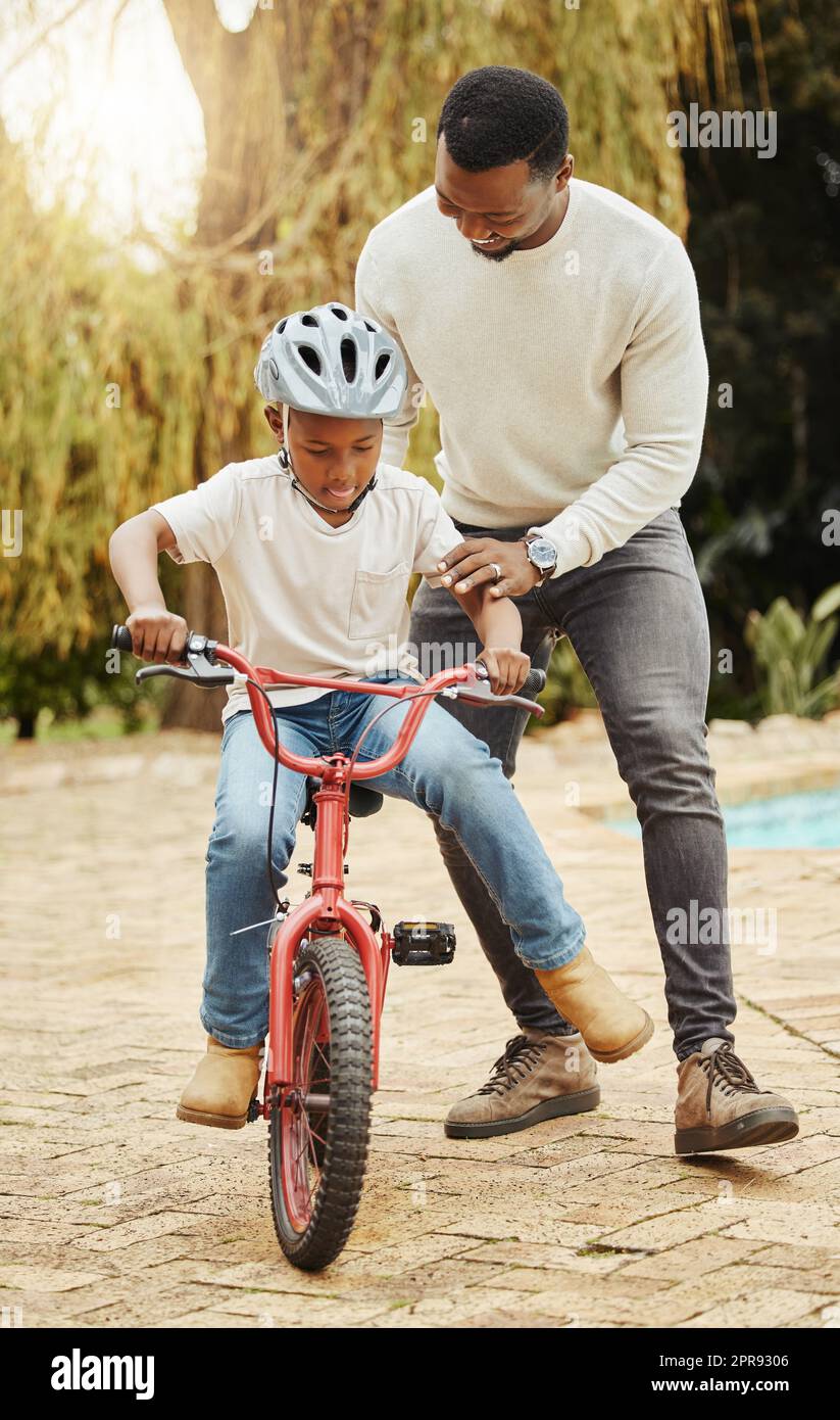 Ein entzückender Junge, der mit seinem Vater im Freien Fahrrad fahren lernt. Stockfoto