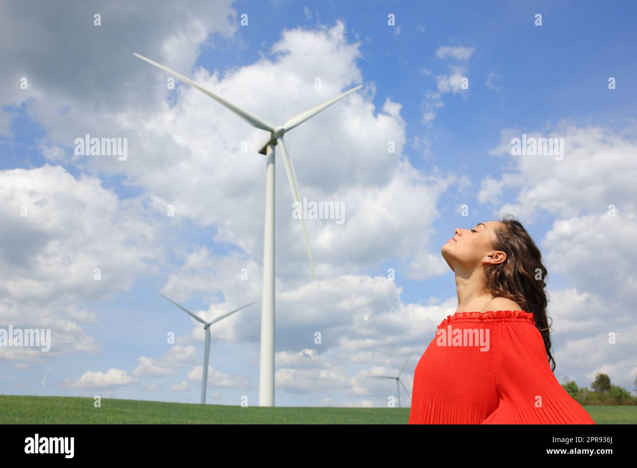 Eine Frau in Rot, die frische Luft in einem Windpark atmet Stockfoto
