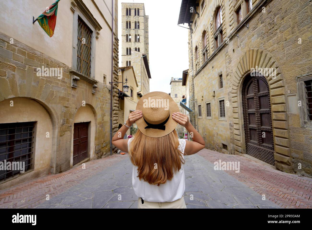 Schöne touristische Mädchen hält Hut zu Fuß in der historischen Stadt Arezzo, Toskana, Italien Stockfoto