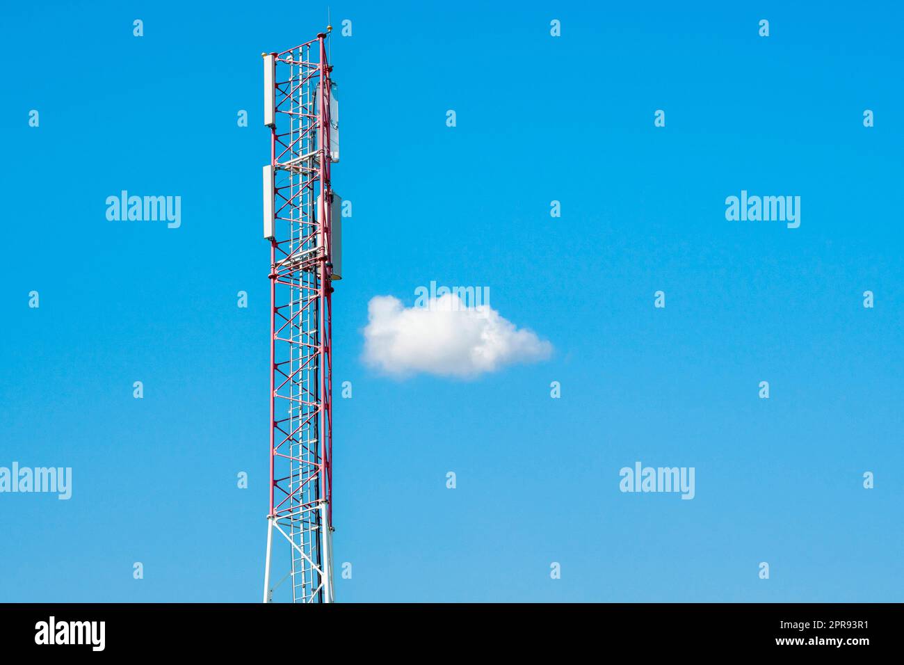 Telekommunikationsturm mit blauem Himmel und einer einzigen weißen Wolke Stockfoto