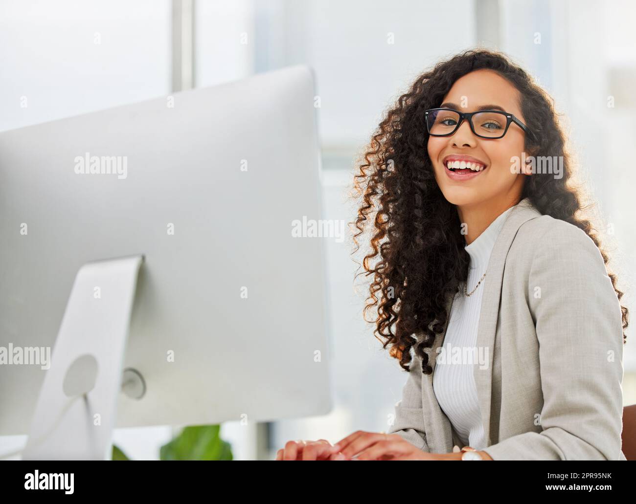 Meine Erfolge halten mich für mehr motiviert. Porträt einer jungen Geschäftsfrau, die in einem Büro am Computer arbeitet. Stockfoto