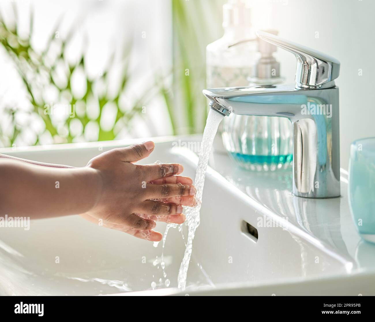 Waschen Sie Ihre Hände und Finger, um alle Keime zu töten, die verharzen. Nahaufnahme eines nicht erkennbaren Jungen, der sich in einem Badezimmer zu Hause am Wasserhahn die Hände wascht. Stockfoto