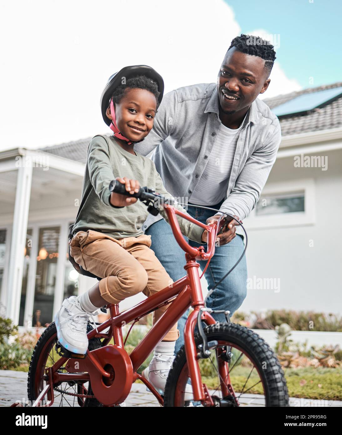 Lebenslange Fähigkeiten entwickeln und dabei jede Menge Spaß haben. Porträt eines entzückenden Jungen, der mit seinem Vater im Freien Fahrrad fahren lernt. Stockfoto