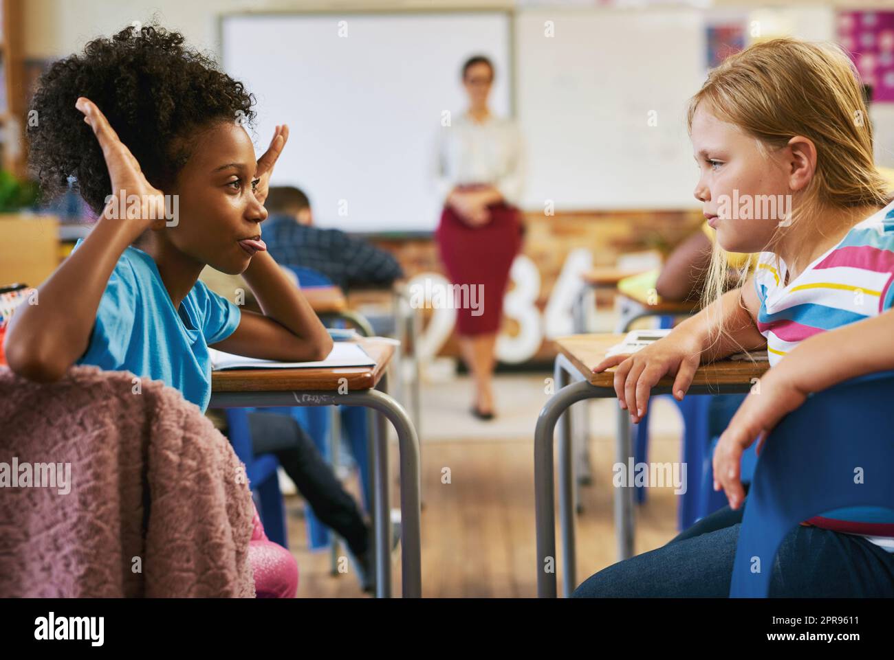 Mobbing muss gestoppt werden. Ein junges Mädchen, das in der Schule im Klassenzimmer sitzt und ihren Klassenkameraden schikaniert. Stockfoto