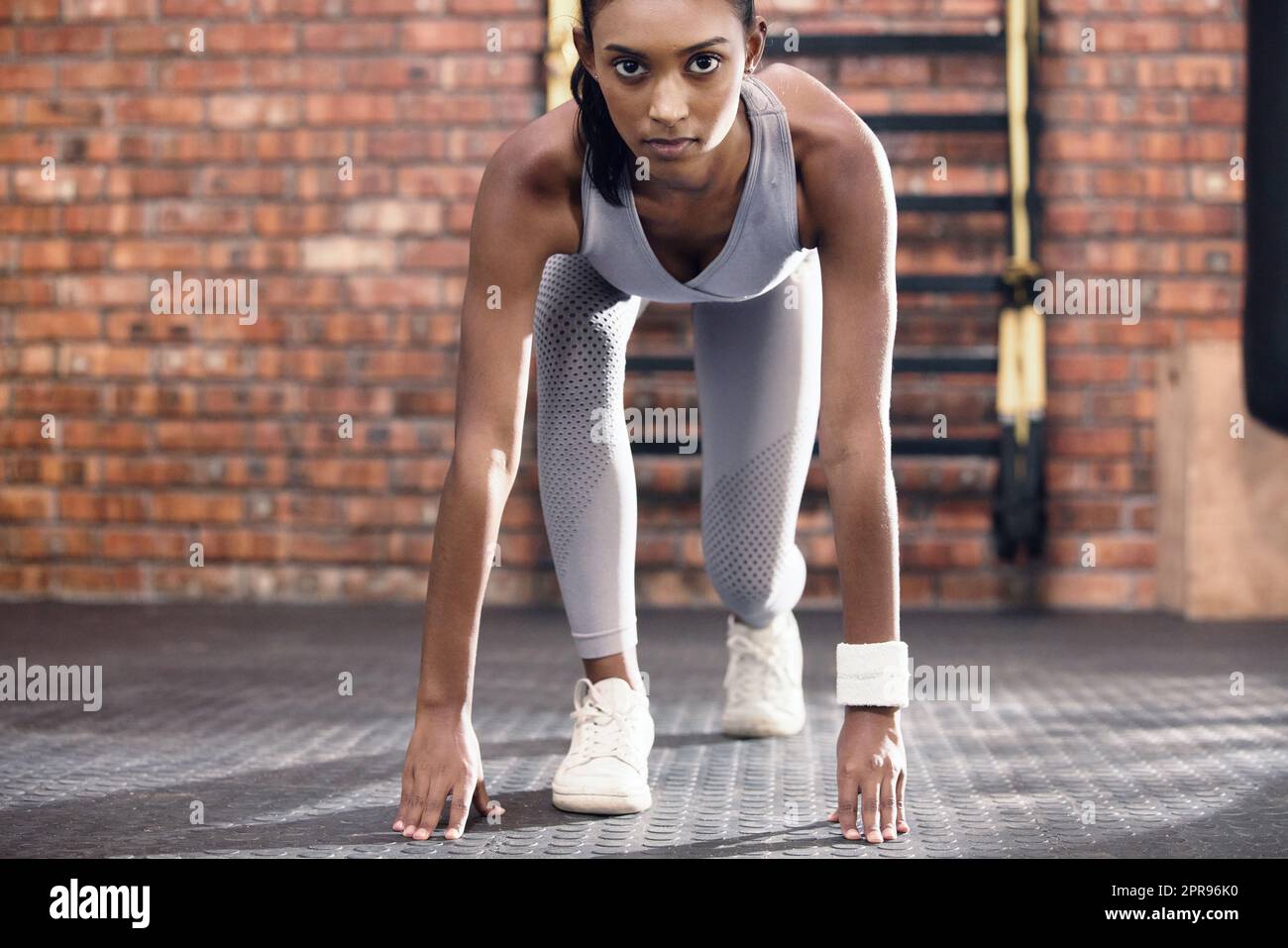 Ihr könnt die ganze Entschlossenheit in ihren Augen lesen. Porträt einer sportlichen jungen Frau in Startposition im Fitnessstudio. Stockfoto