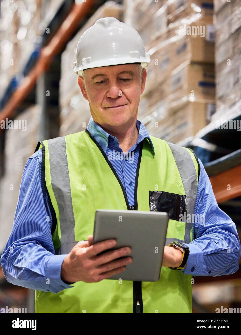 Ohne harte Arbeit kann es nicht gelingen. Ein reifer Mann, der ein digitales Tablet benutzt, während er in einem Lager arbeitet. Stockfoto