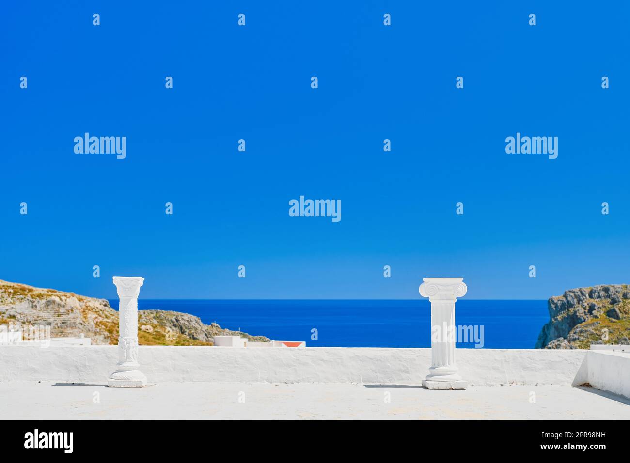 Zwei antike Säulen auf dem Dach des Hauses. Blick vom Dach des Hauses auf die Stadt Lindos, das smaragdgrüne Meer, die Insel Rhodos. Urlaub A Stockfoto