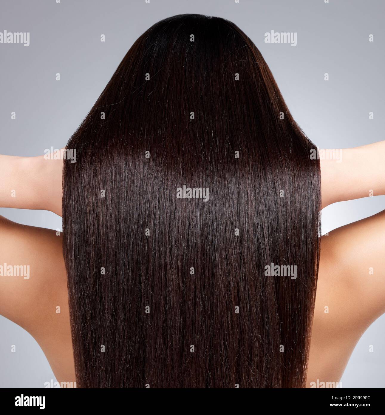 Schau dir diesen gesunden Glanz an. Rückansicht einer jungen Frau mit langen seidigen Haaren, die vor einem grauen Hintergrund posiert. Stockfoto