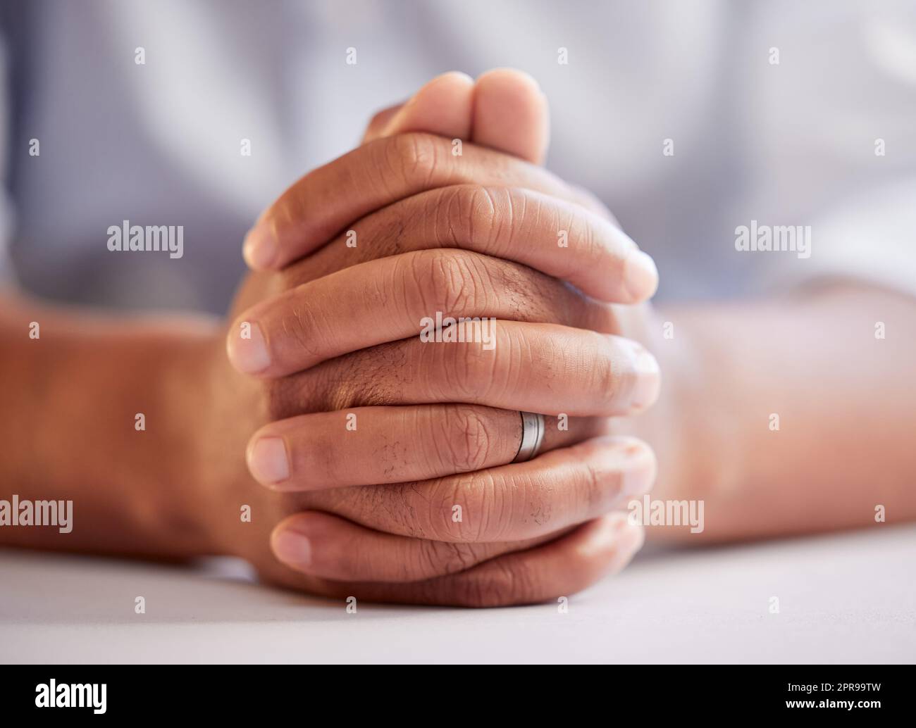 Ein Mann des Glaubens. Ein unkenntlich sitzender Mann mit gebetteten Händen. Stockfoto