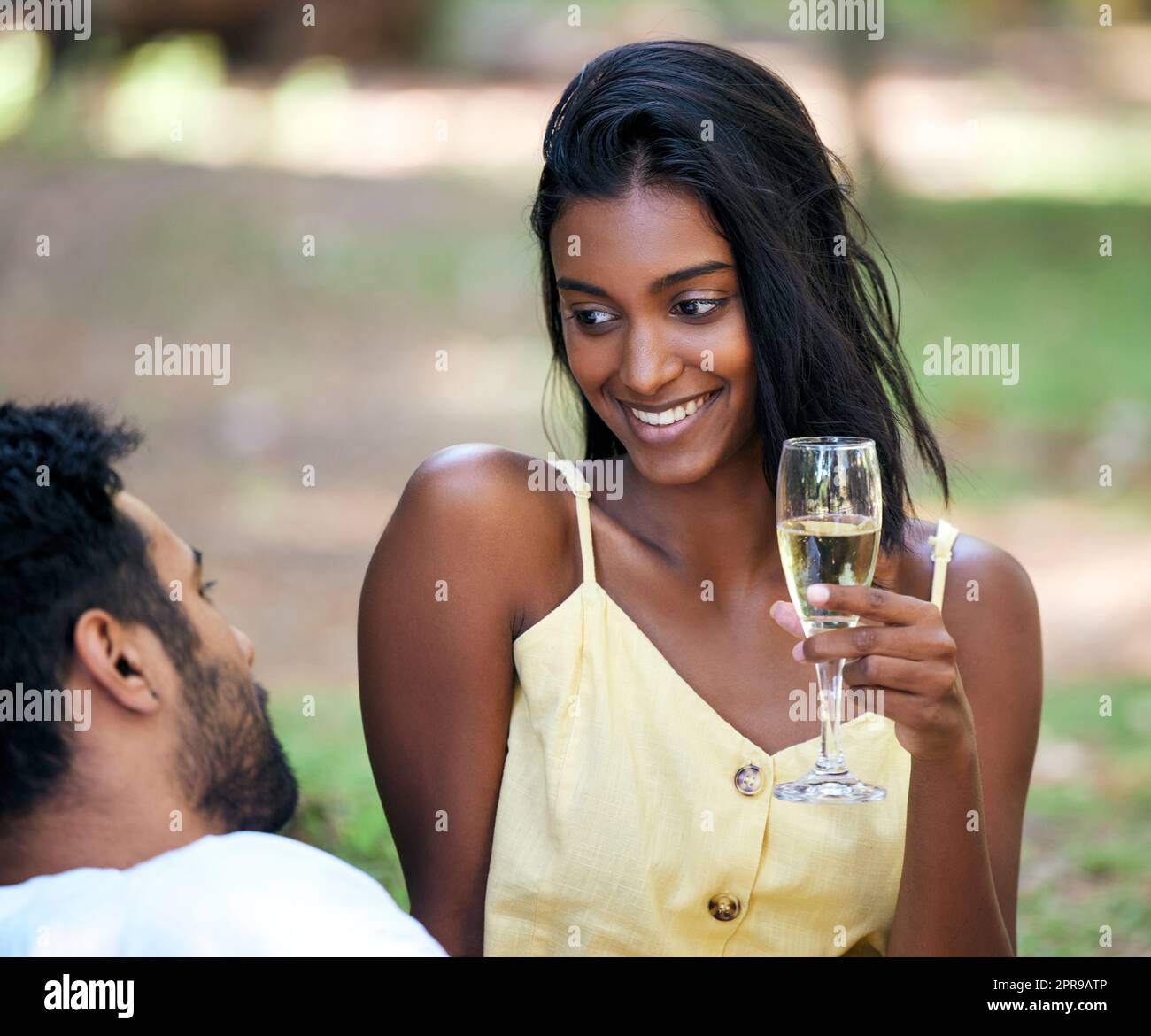 Er weiß, wie ich mich wohl fühlen kann. Eine junge Frau, die Champagner trinkt, während sie im Park ein Date abhielt. Stockfoto