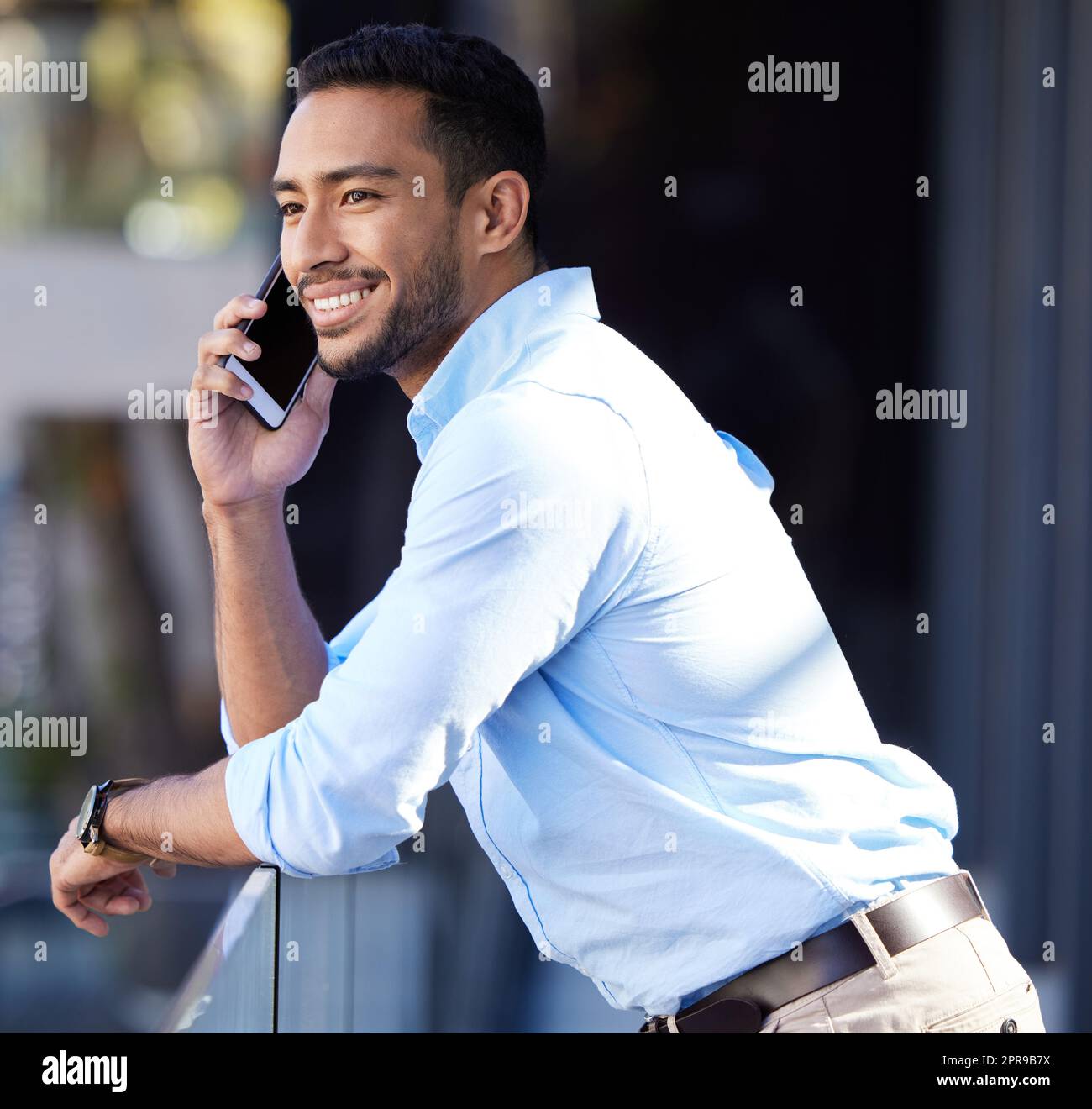 Es ist so toll von Ihnen, mich anzurufen. Ein junger Geschäftsmann, der auf einem Handy spricht, während er auf einem Balkon vor einem Büro steht. Stockfoto