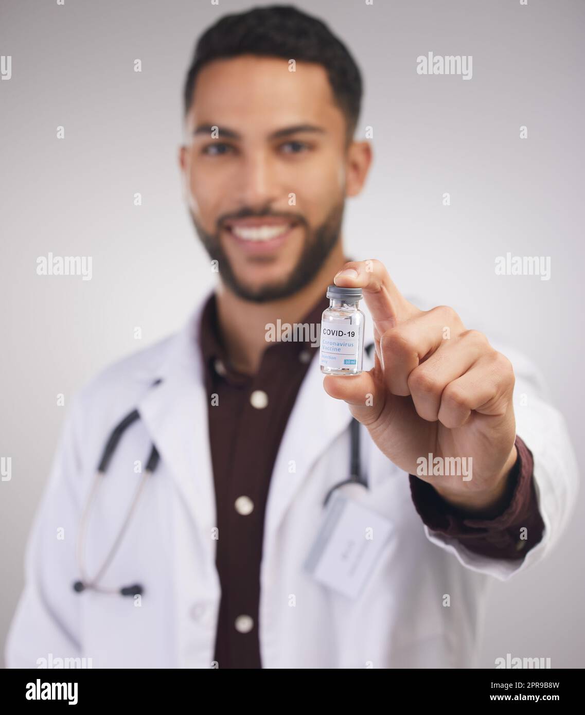 Ein Lebensretter in einer Flasche. Ein hübscher junger Arzt, der allein im Studio steht und eine Ampulle des Covid-Impfstoffs hält. Stockfoto