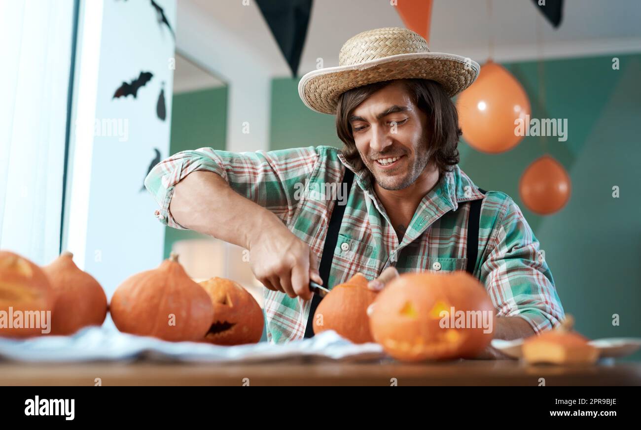 Nun essen Sie bald eine Menge Kürbis. Ein junger Mann, der zu Hause einen Kürbis schnitzt. Stockfoto