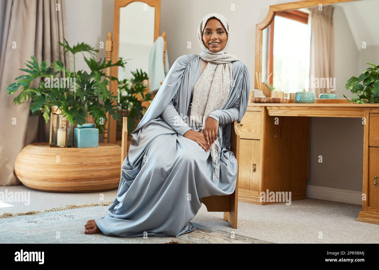 Sie können sich traditionell kleiden und immer noch gut aussehen. Eine junge muslimische Frau sitzt in der Lounge zu Hause. Stockfoto