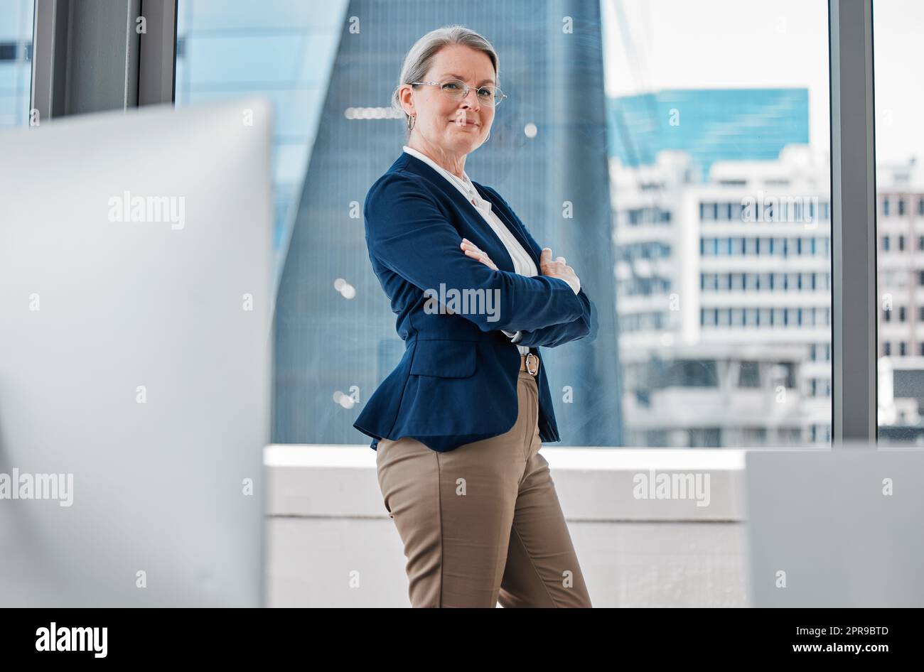 Im bringt dieses Geschäft auf die nächste Ebene. Eine reife Geschäftsfrau allein im Büro stehend mit ihren Armen gefaltet. Stockfoto