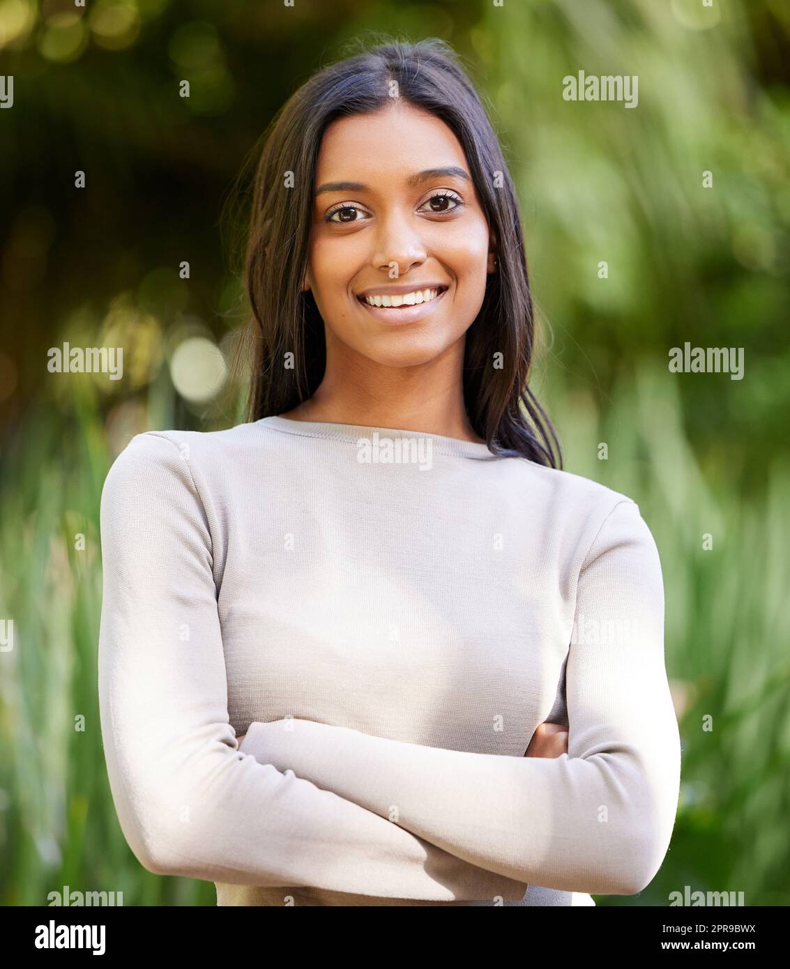 Lächle und die Welt lächelt dich wieder an. Eine schöne junge Frau lächelt, während sie draußen steht. Stockfoto