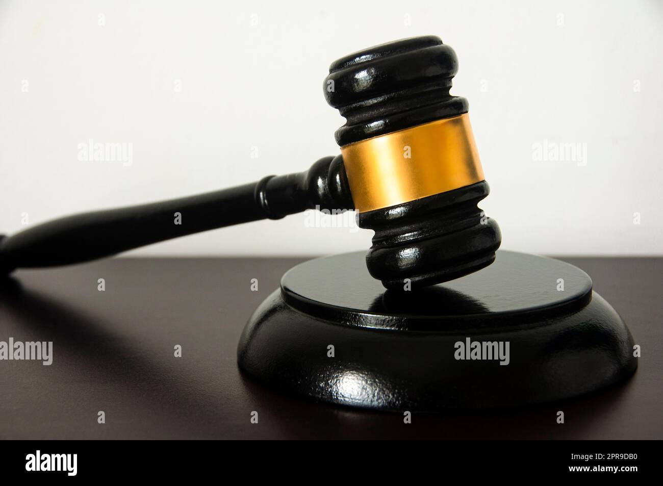 Gerader Blick auf den Anwaltshammer auf einem Holztisch mit weißem Hintergrund. Stockfoto