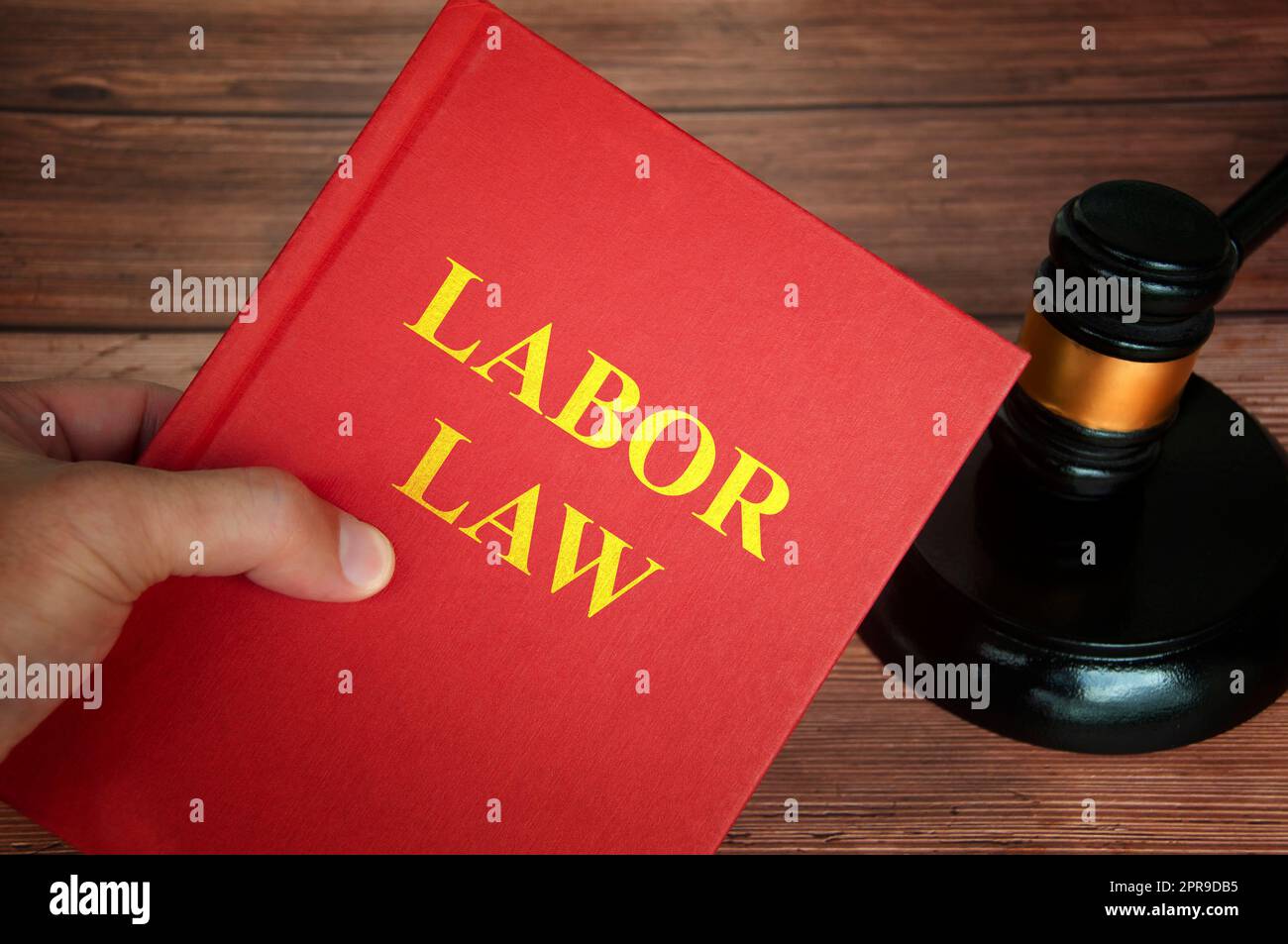 Arbeitsrechtlicher Text im Gesetzbuch mit Richterhammer auf Holzschreibtischhintergrund. Stockfoto